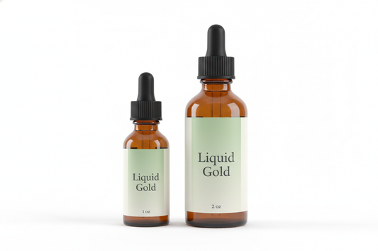 Create a studio product photo of two amber dropper bottles, 1 oz and 2 oz, both with black ribbed dropper tops. The labels must match exactly: soft green to cream gradient, centered serif text reading ‘Liquid Gold’ in a Baskerville or Garamond style font. At the bottom of each label, print the correct size as ‘1 oz’ and ‘2 oz’ in the same serif font. Place both bottles side by side on a white background with soft shadows. Do not change the font or text.